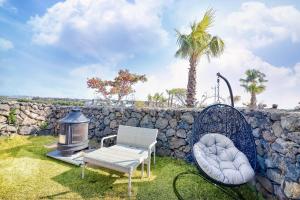 Eine Steinmauer mit zwei Stühlen und einer Heizung in der Unterkunft Seogwipo Dawa Pool Villa Pension in Seogwipo + 10 Fotos