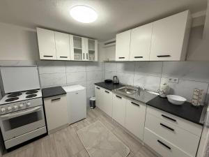 a kitchen with white appliances and white cabinets at Apartments AZRA in Konjic