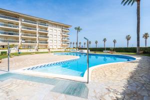 a swimming pool in front of a building with palm trees at Los Flamencos I in Miami Platja