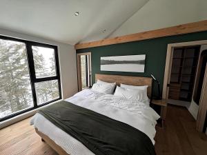 a bedroom with a large bed and two windows at Scandinavian Luxury Chalet, Hot Tub, Private Dock, Sleeps 14!! Min 32 nights in Sainte-Lucie-de-Doncaster +18 photos
