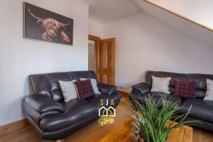 a living room with two leather couches and a painting at Albyn Retreat - SJA Stays - 1 Bed Apartment in Aberdeen