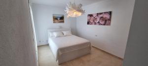 niewielka sypialnia z białym łóżkiem i żyrandolem w obiekcie Mijas Golf penthouse w mieście Santa Fe de los Boliches +19 zdjęć