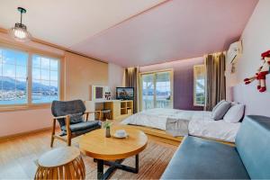 a bedroom with a bed and a couch and a table at Tongyoung Mongdolhouse Pension in Tongyeong