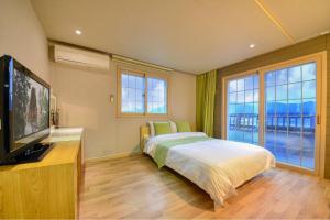 a bedroom with a bed and a flat screen tv at Tongyoung Mongdolhouse Pension in Tongyeong