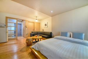 a bedroom with a bed and a couch and a table at Tongyoung Mongdolhouse Pension in Tongyeong