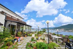 a patio with tables and chairs and a view of the water at Tongyoung Mongdolhouse Pension in Tongyeong