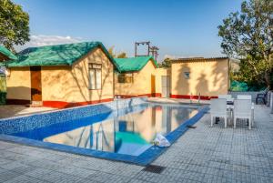 a swimming pool with chairs and a house at The Wild Orchid Resort Corbett in Rāmnagar