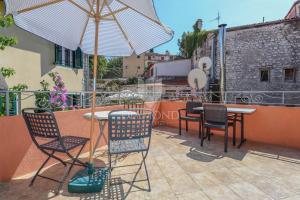 a patio with a table and chairs and an umbrella at Villa Augusta Ferri in Rovinj