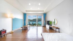 a bedroom with a bed and a living room at Tongyeong Maremio Oceanview Pension in Tongyeong