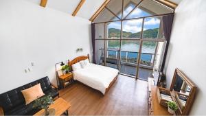 a bedroom with a bed and a large window at Tongyeong Maremio Oceanview Pension in Tongyeong