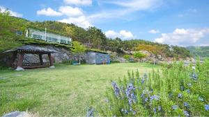 a yard with a stone building and a gazebo at Tongyeong Maremio Oceanview Pension in Tongyeong