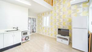 a kitchen with a refrigerator and a tv on a wall at Pocheon Swimpyo Pension in Pocheon