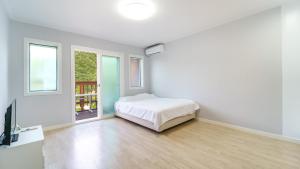 a white bedroom with a bed and a window at Pocheon Swimpyo Pension in Pocheon