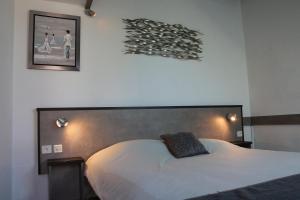 1 dormitorio con cama blanca y almohada negra en Motel du Val André, en Pléneuf-Val-André
