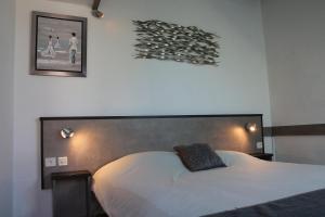 a bedroom with a white bed with a black pillow on it at Motel du Val André in Pléneuf-Val-André