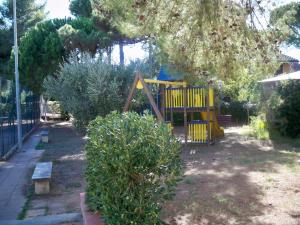 un parco giochi in un cortile con un albero di Residence Airone a Orbetello