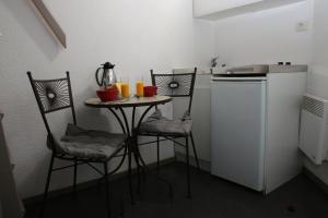a small kitchen with a table with two chairs and orange juice at Motel du Val André in Pléneuf-Val-André +9 photos