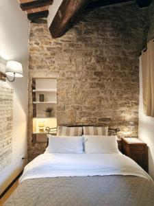 Un dormitorio con una cama grande con una pared de ladrillo. en La Tana del Priore, en Perugia