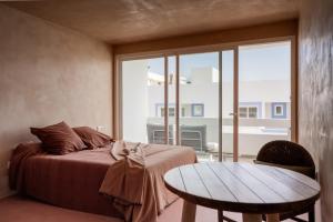 a bedroom with a bed and a table and a window at Formentera Especial in La Savina