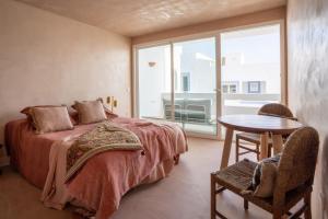 a bedroom with a bed and a table and a window at Formentera Especial in La Savina