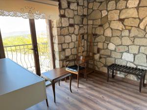 a room with a table and chairs and a stone wall at Bademli Han Otel in Ulucak