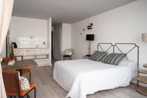 a bedroom with a white bed and a desk and chairs at Formentera Especial in La Savina