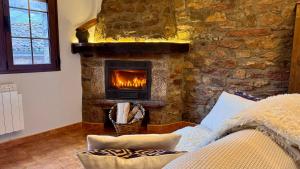 chimenea de piedra en la sala de estar con sofá en Apartamentos y Casas de Aldea La Pornacal, en Villar de Vildas