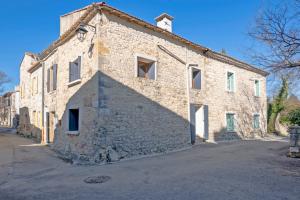 - un ancien bâtiment en pierre avec une grande ombre dans l'établissement Le Cœur de Garrigues - Piscine Privée, à Garrigues-et-Sainte-Eulalie