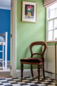 a chair sitting in a room with a green wall at Chez Nous - central Maisonette - Bath Surrounds in Bradford on Avon