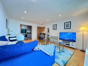 a living room with a blue couch and a tv at River View London Eye Vauxhall 2 Bedroom Apartment in London