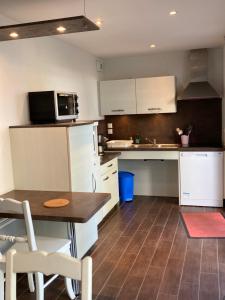 a kitchen with white cabinets and a table and a microwave at Le Sherman in Colleville-sur-Mer