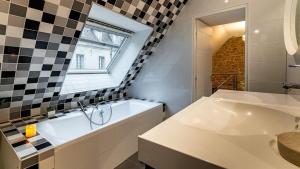 un bagno con vasca, lavandino e finestra di La Maison Mercier a Digione