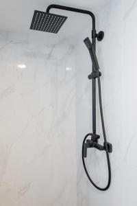 une douche avec un pommeau de douche noir sur un mur dans l'établissement Palanga Beach Apartments Daukanto, à Palanga 13 autres photos