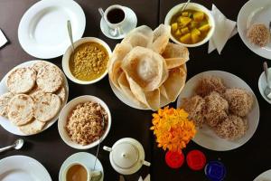 a table with plates of food and cups of coffee at Rohans place in Nattandiya