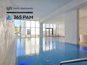 a swimming pool with blue water in a building at 365PAM - Apartament LET'S SEA z widokiem na morze - BASEN, JACUZZI, SAUNA, SIŁOWNIA, STREFA CHILL, PARKING W CENIE in Gąski