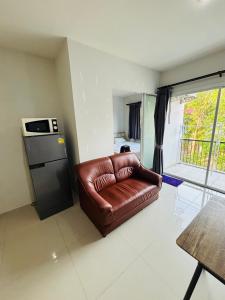 Phuket naka Condon-41无边泳池免费上网免费停车位 في فوكيت تاون: أريكة جلدية بنية في غرفة المعيشة مع نافذة