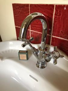 a silver faucet on a white sink with a clock at Tivauche in Corsaint