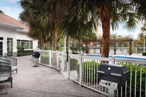 a white fence with palm trees and a swimming pool at Homewood Suites by Hilton Orlando Airport in Orlando +41 photos