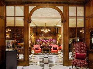 a lobby with a table and chairs and a chandelier at Fairmont Hotel Vier Jahreszeiten in Hamburg