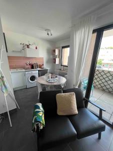 ein Wohnzimmer mit einer schwarzen Couch und einer Küche in der Unterkunft Grand Studio avec Parking et Wifi in Castelnau-le-Lez