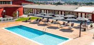 an outdoor pool with umbrellas and chairs and a hotel at Motel Caldas in Caldas de Reis