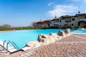 a swimming pool with rocks next to a building at Appartamento La Quiete in Polpenazze del Garda