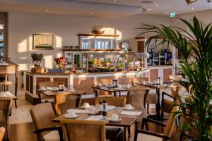 Un restaurante con mesas y sillas y un mostrador. en Precise Resort Schwielowsee - Hotel, en Werder