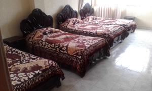 a group of four beds sitting in a room at Hostal Lesly Salomé in Tulcán