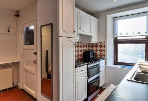 セネンにあるFinest Retreats - Bishop Rockの白いキャビネットとコンロ付きオーブンを備えたキッチン