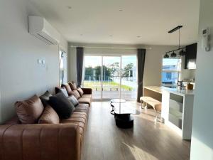 un soggiorno con un divano marrone e una cucina di Brand new Lakeside cozy room kaka a Taupo