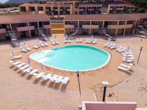 an empty swimming pool with lounge chairs and a resort at Rocce Rosse Isola Rossa in Isola Rossa