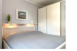 a white bedroom with a bed and a dresser at Goosbrink Wohnung 13 in Boltenhagen