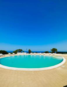 a large swimming pool with chairs and the ocean at Rocce Rosse Isola Rossa in Isola Rossa +16 photos