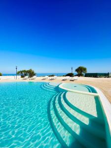 a swimming pool next to a sandy beach at Rocce Rosse Isola Rossa in Isola Rossa